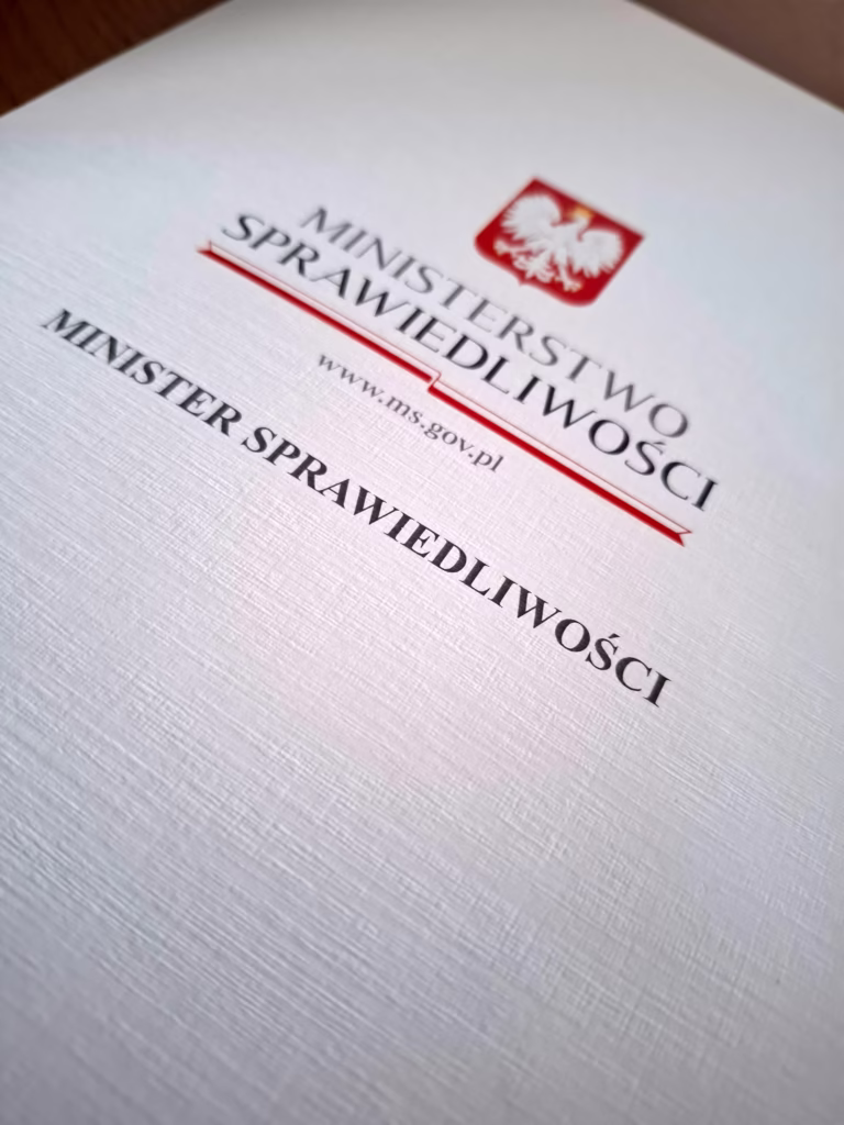 Zbliżenie na okładkę dokumentu polskiego Ministerstwa Sprawiedliwości z godłem.
